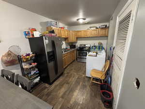Kitchen featuring dark wood-type flooring, stainless steel appliances, and brown cabinets