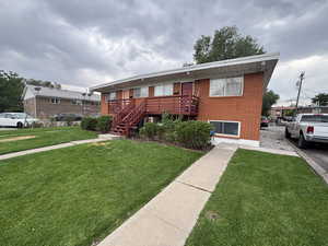 View of front of house featuring brick siding, a front lawn, and stairway