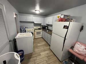 Kitchen featuring white appliances, wood tiled floors, washer / dryer, and dark countertops