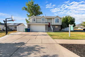 Split foyer home with brick siding, an attached garage, and driveway