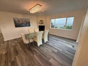 Dining area with wood finished floors, a chandelier, and a large fireplace