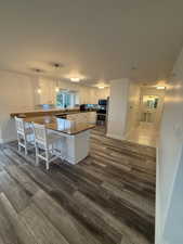 Kitchen with a peninsula, dark wood-style floors, white cabinets, and a kitchen bar