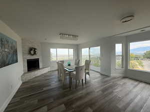 Dining space featuring dark wood-style floors and a stone fireplace