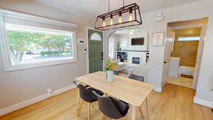 Dining space featuring arched walkways, light wood-style floors, and a glass covered fireplace