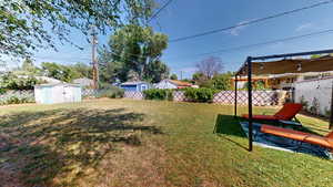 Fenced backyard featuring a storage unit