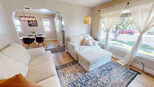 Living area featuring arched walkways, wood finished floors, and a chandelier