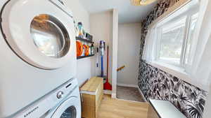 Washroom featuring stacked washer and clothes dryer and light wood-style flooring