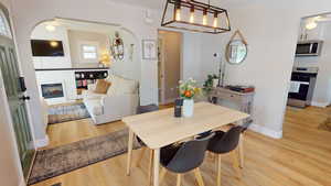 Dining area with ceiling fan, arched walkways, and light wood-style floors