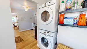 Washroom featuring estacked washer and dryer, wood finished floors, and a ceiling fan