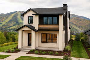 Contemporary home featuring a mountain view, brick siding, a balcony, and a front yard