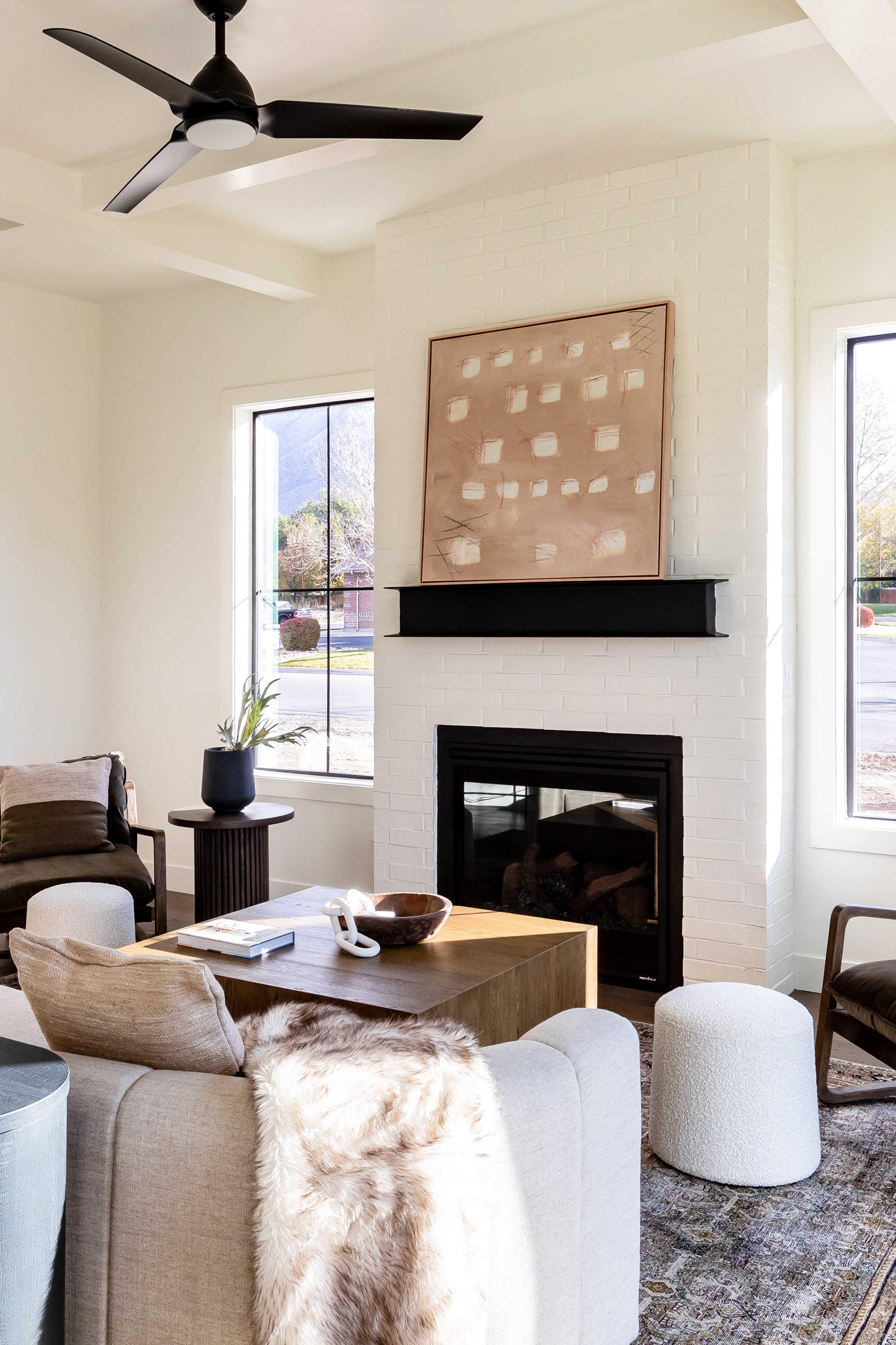 Living room with a fireplace, a ceiling fan, and plenty of natural light