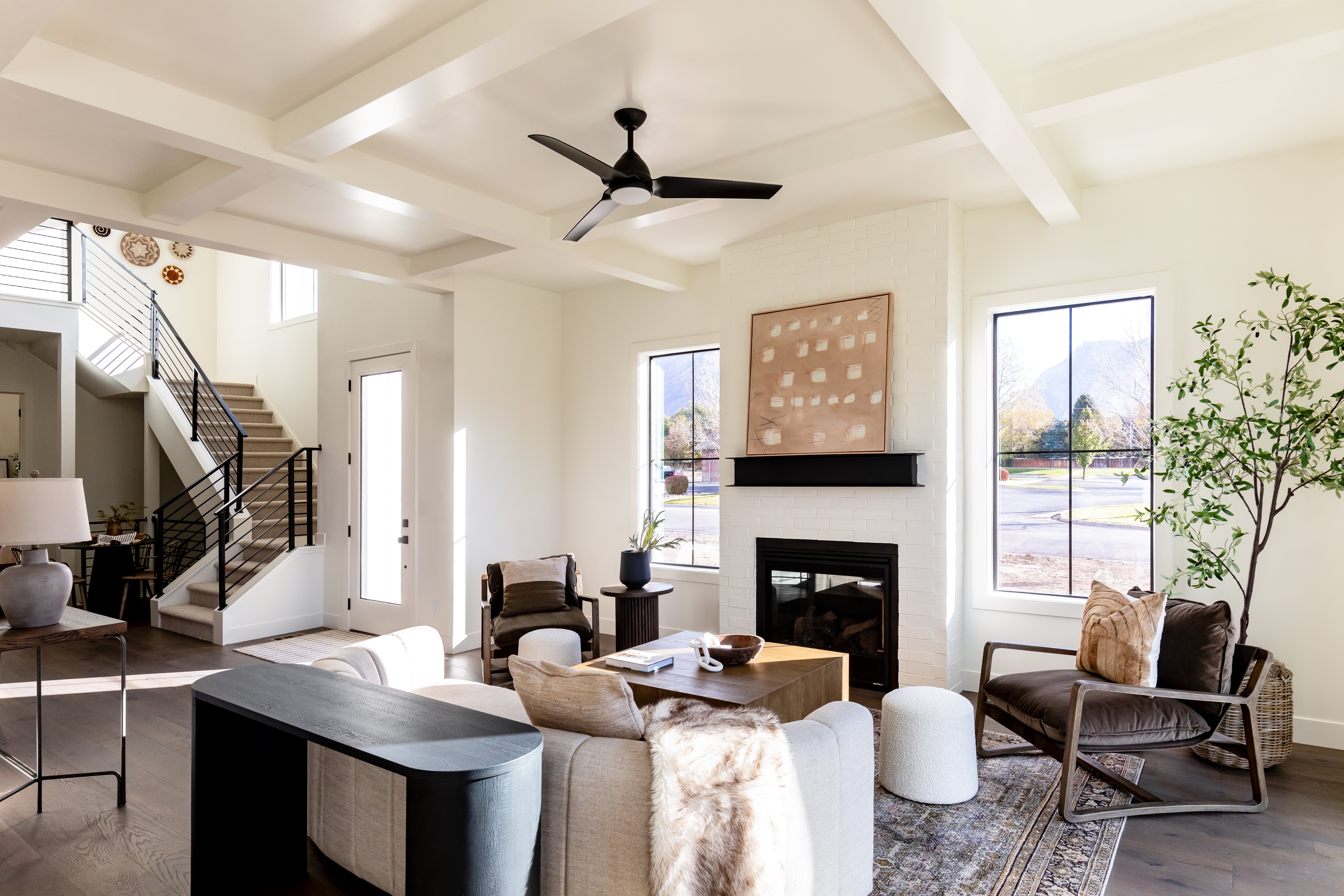 Living room featuring coffered ceiling, plenty of natural light, a fireplace, wood finished floors, and beamed ceiling