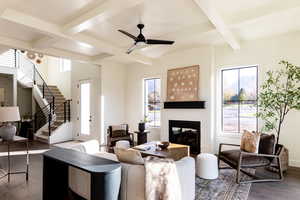 Living room featuring coffered ceiling, plenty of natural light, a fireplace, wood finished floors, and beamed ceiling