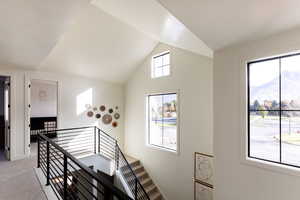 Staircase featuring vaulted ceiling and carpet flooring