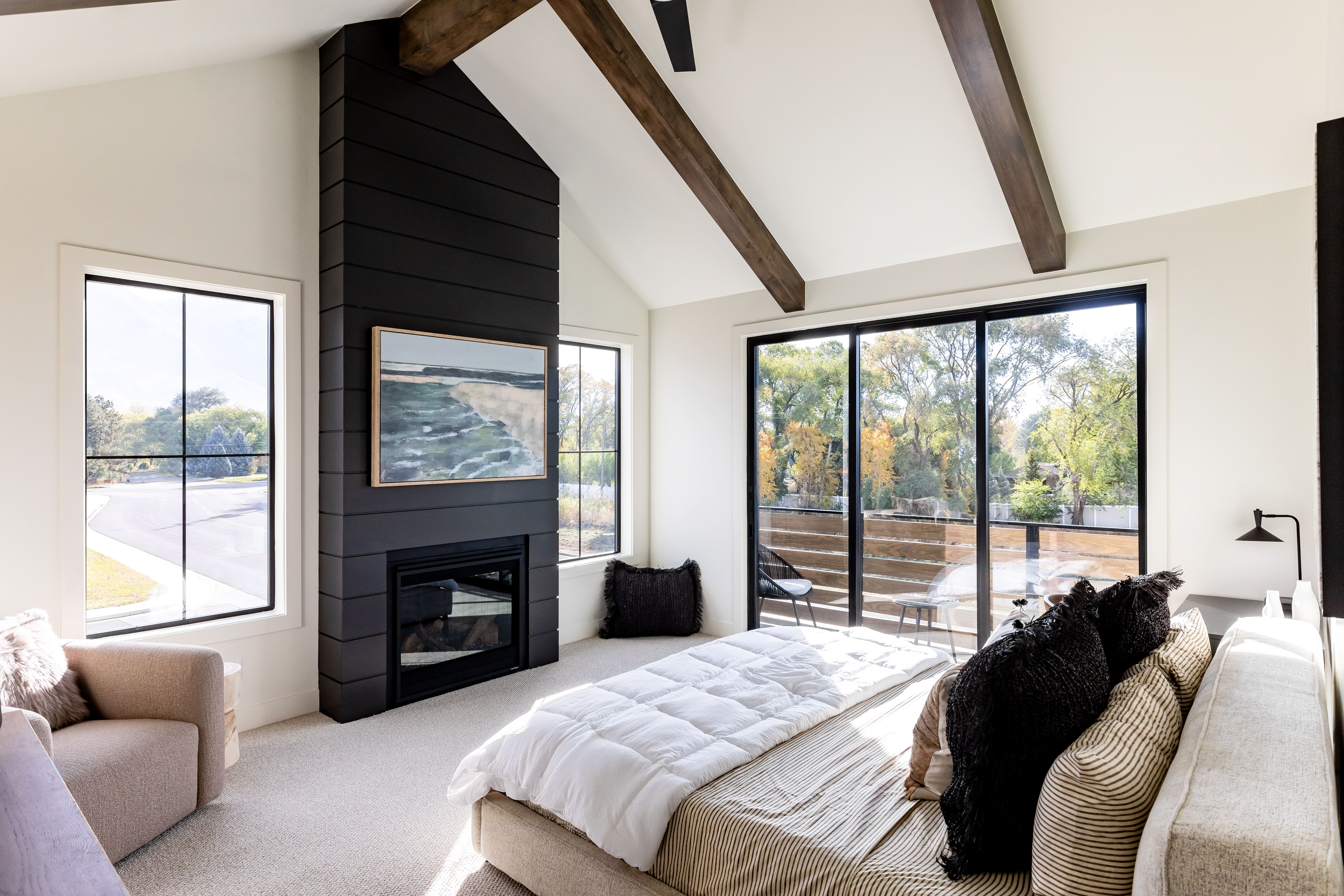 Bedroom with access to outside, carpet floors, beamed ceiling, a large fireplace, and high vaulted ceiling