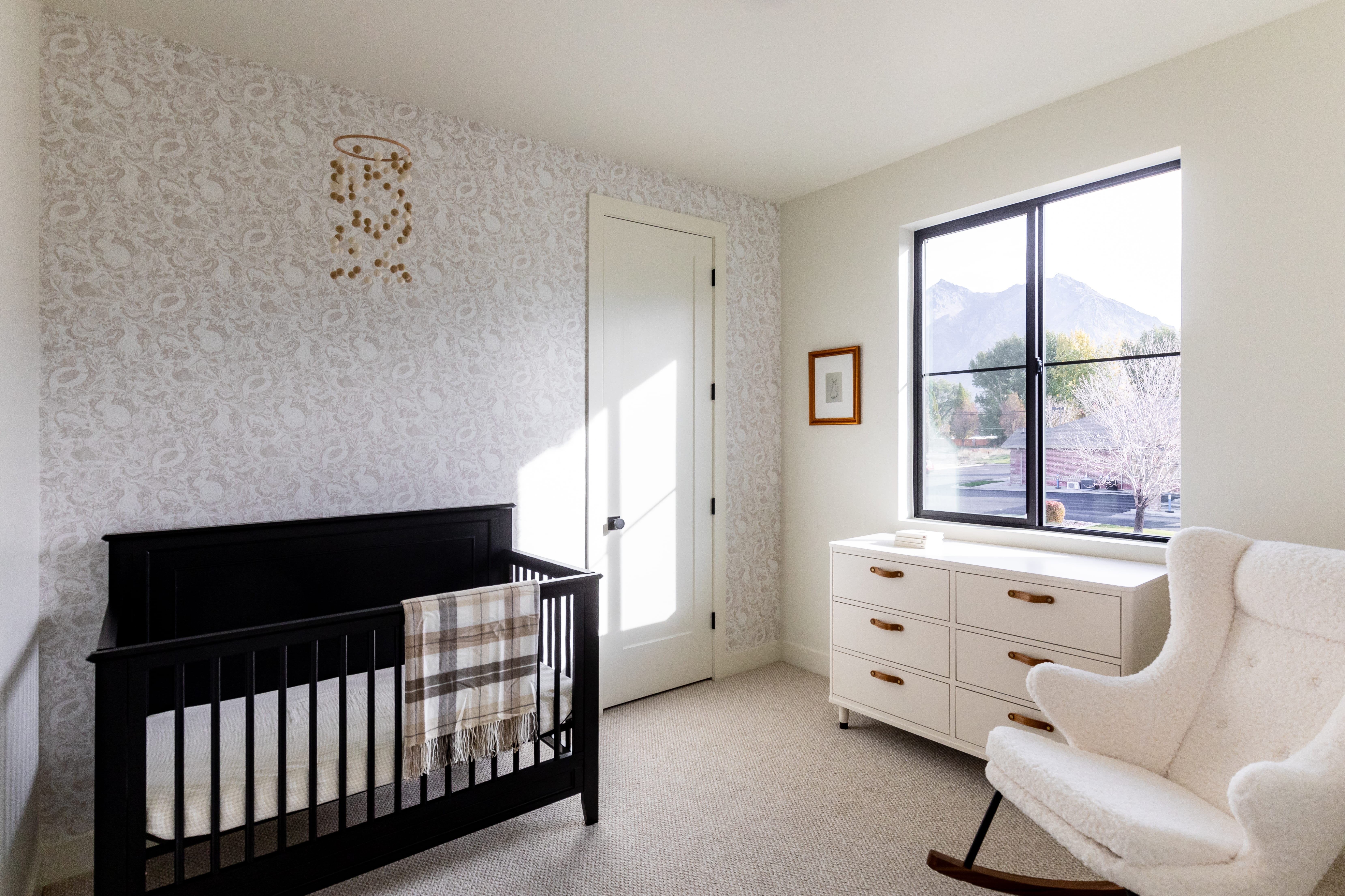 Bedroom with light carpet, a nursery area, a mountain view, and wallpapered walls