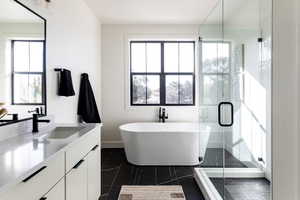 Full bath featuring vanity, a freestanding bath, and a stall shower