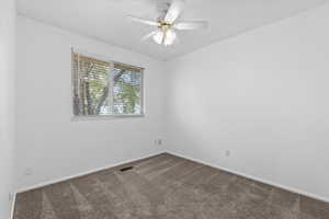 Spare room featuring dark carpet and ceiling fan