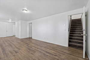 Unfurnished living room with stairway and dark wood-style floors