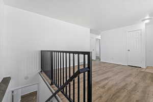 Corridor with an upstairs landing, wood finished floors, and a textured ceiling