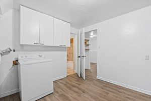 Laundry area featuring washer / dryer, wood finished floors, and cabinet space