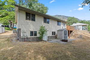 Rear view of property with a storage shed, a mountain view, and a yard