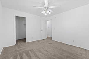 Unfurnished bedroom featuring carpet, a spacious closet, and ceiling fan