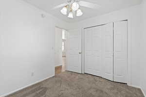 Unfurnished bedroom featuring carpet floors, a closet, and a ceiling fan