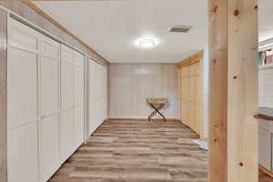 Hallway featuring light wood-type flooring and wood walls