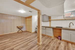Basement featuring light wood-style flooring and wood walls