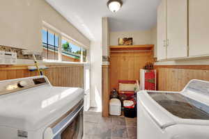 Laundry area with washing machine and clothes dryer and wood walls