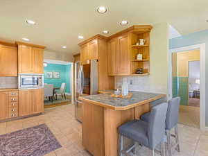 Kitchen with a breakfast bar, stainless steel appliances, light tile patterned flooring, a peninsula, and recessed lighting