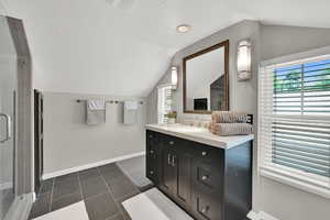 Bathroom featuring lofted ceiling, vanity, a shower stall, and tile patterned flooring