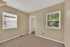 Carpeted empty room with baseboards and vaulted ceiling