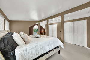 Bedroom with light colored carpet and two closets