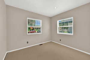 Carpeted spare room with baseboards and recessed lighting