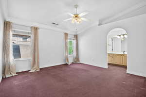 Empty room featuring dark carpet, a ceiling fan, and crown molding