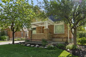 View of front of brick home, a front yard, and covered porch