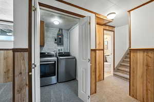 Laundry area with carpet flooring, independent washer and dryer, electric panel, cabinet space, and wood walls