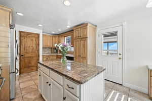 Kitchen with a kitchen island, freestanding refrigerator, light tile patterned flooring, recessed lighting, and tasteful backsplash