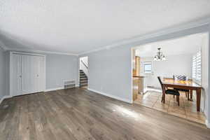 Living area featuring a chandelier, stairway, a textured ceiling, hardwood / wood-style flooring, and crown molding