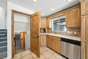 Kitchen featuring stainless steel dishwasher, light countertops, tasteful backsplash, light tile patterned floors, and recessed lighting
