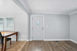 Foyer entrance featuring wood finished floors, crown molding, and a textured ceiling