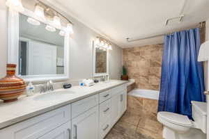 Full bathroom featuring double vanity, a textured ceiling, tile patterned floors, and tiled shower / bath combo