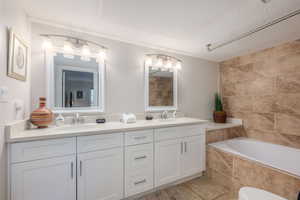Full bath with double vanity, tiled tub, and a textured ceiling