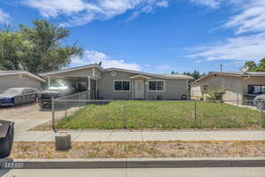 View of front of property with a fenced front yard, a carport, and driveway