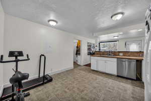 Kitchen featuring dishwasher, white cabinetry, a textured ceiling, electric panel, and freestanding refrigerator