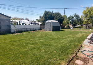 Fenced backyard featuring a storage shed