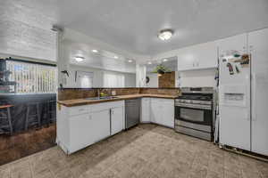 Kitchen featuring a textured ceiling, appliances with stainless steel finishes, white cabinets, dark countertops, and recessed lighting