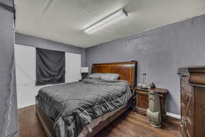 Bedroom with wood finished floors, a textured wall, and a textured ceiling